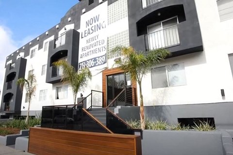 A modern building with a sign that says "Now Leasing: Newly Renovated Apartments" and a phone number.