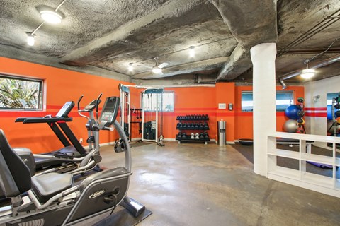 A gym with orange walls and a variety of exercise equipment.