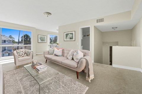 A living room with a glass coffee table and a couch with a throw blanket on it.