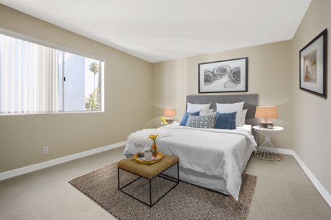 A bedroom with a large bed and a small table with a vase on it.