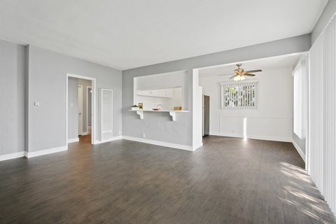 A spacious room with a ceiling fan and hardwood floors.