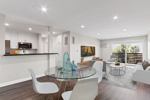 A modern dining room with a glass table and white chairs.