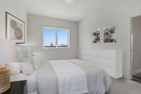 A bedroom with a large bed and a window overlooking a tree-filled landscape.