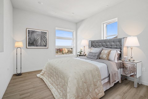 A bedroom with a large bed and a window overlooking the city.