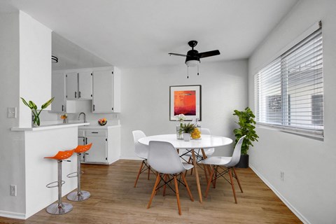 A kitchen with a white table and chairs and a ceiling fan.