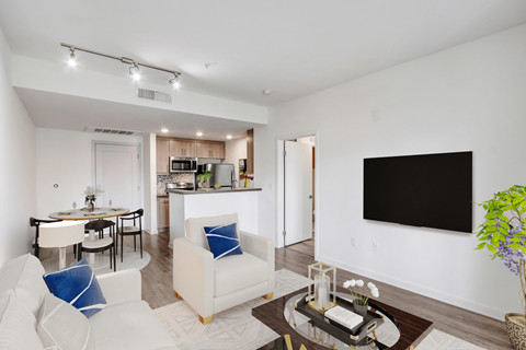 A modern living room with a white sofa and a black TV on the wall.