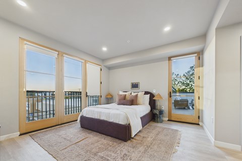 A bedroom with a large bed and a view of the ocean through the sliding glass doors.