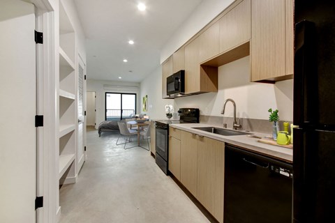 A modern kitchen with dark brown cabinets and a black refrigerator.