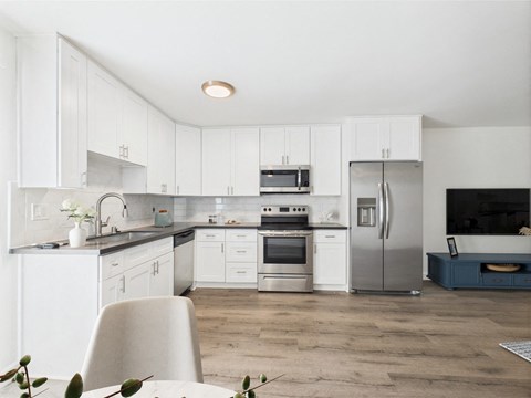 A modern kitchen with white cabinets and stainless steel appliances.