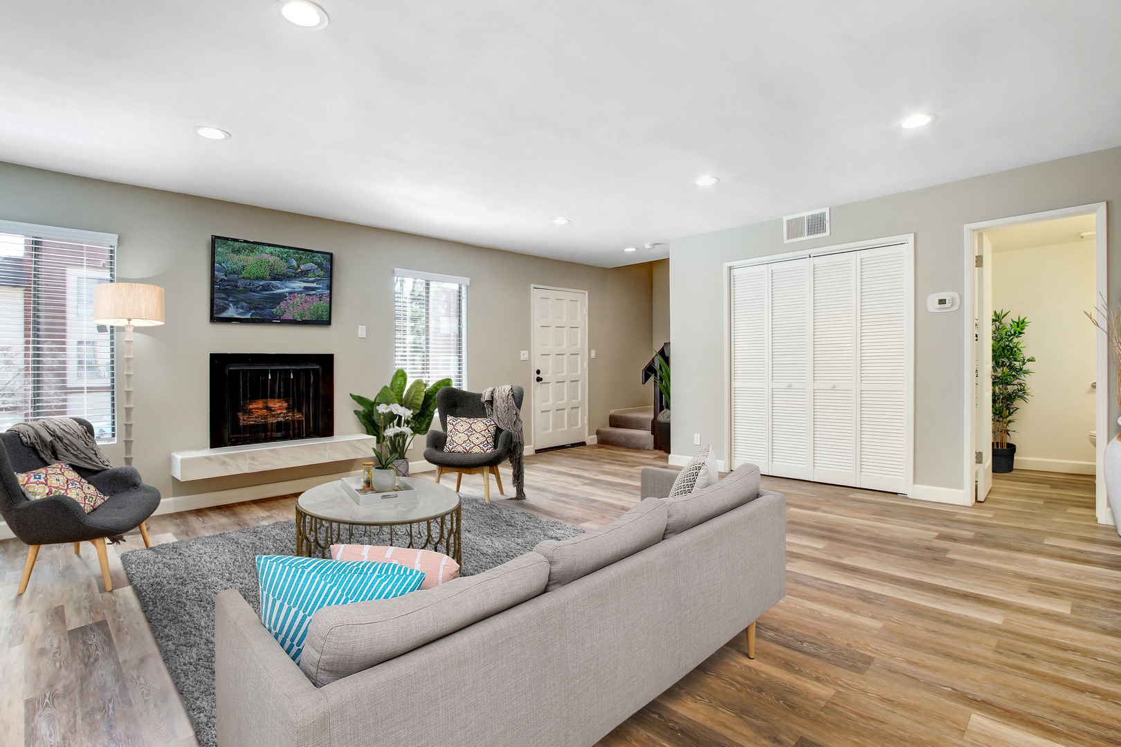 A living room with a grey couch, a fireplace, and a painting on the wall.