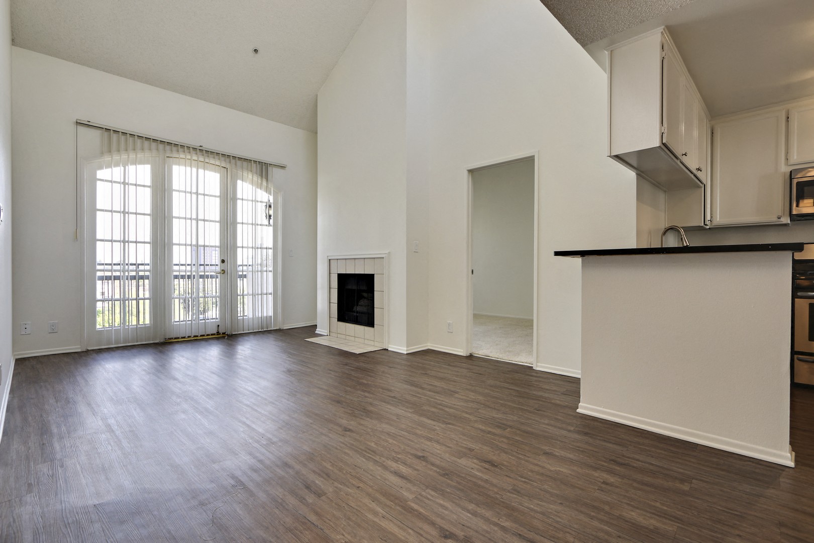 A large, empty living room with wood flooring and a fireplace.