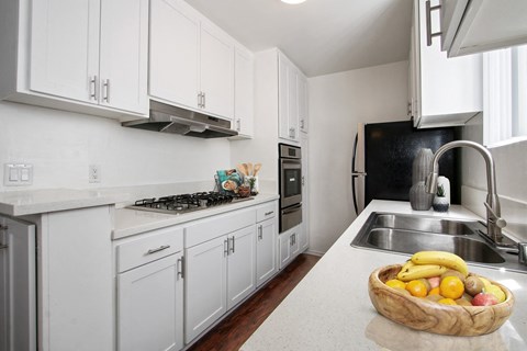 A kitchen with white cabinets and a bowl of fruit on the counter.