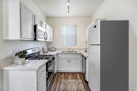 A kitchen with white cabinets and a black refrigerator.