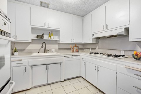 A white kitchen with a stove top oven and a microwave.