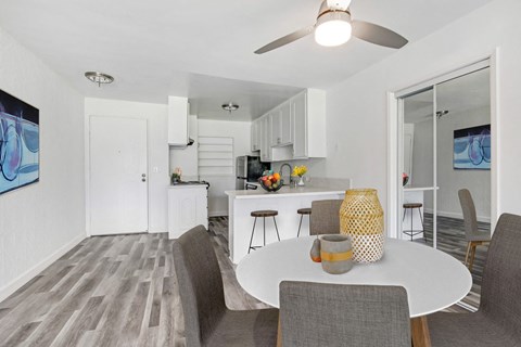 A modern dining room with a white table and grey chairs.