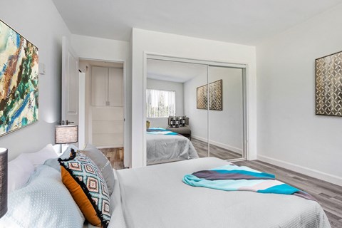 A bedroom with a large bed and a mirror on the wall.