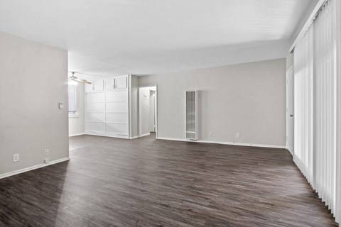 A spacious room with wooden flooring and white walls.