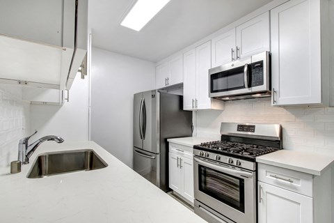 A kitchen with a stainless steel refrigerator, microwave, oven, and sink.