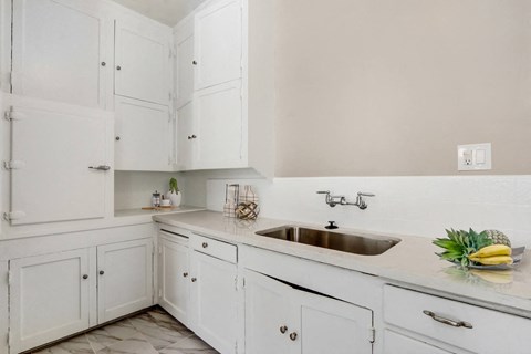 A white kitchen with a sink and a counter.