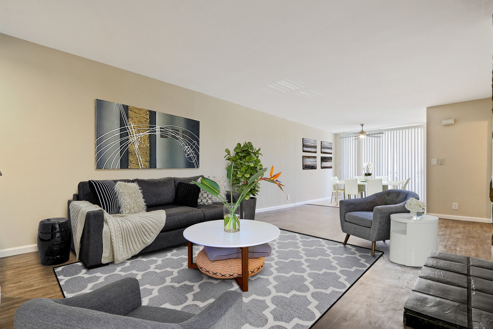 A living room with a grey couch and a painting on the wall.
