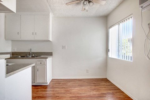 A kitchen with white cabinets and a wooden floor.