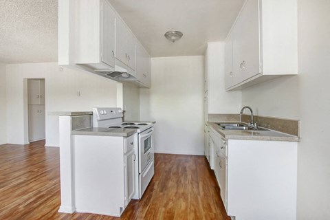 A kitchen with white appliances and wooden floors.