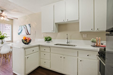 A kitchen with white cabinets and a wooden floor.