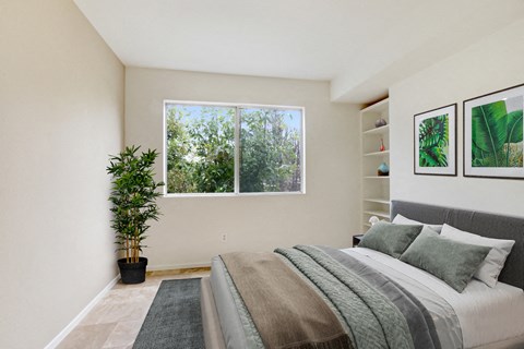 A bedroom with a large bed and a potted plant.