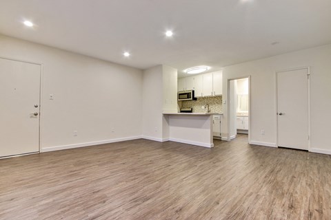 A spacious room with wooden flooring and white walls.