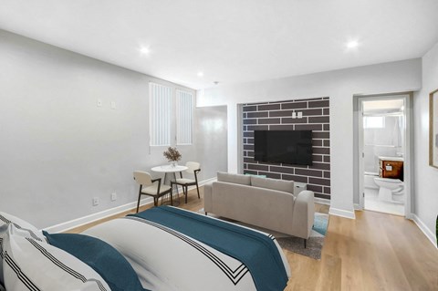 A living room with a grey couch and a television on the wall.