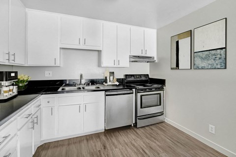 A modern kitchen with white cabinets and stainless steel appliances.
