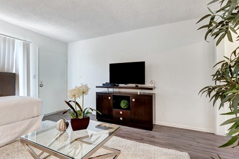 A living room with a glass coffee table and a flat screen TV.