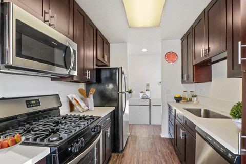 A kitchen with dark brown cabinets and a black stove top.