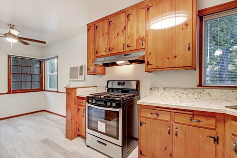A kitchen with wooden cabinets and a stove top oven.