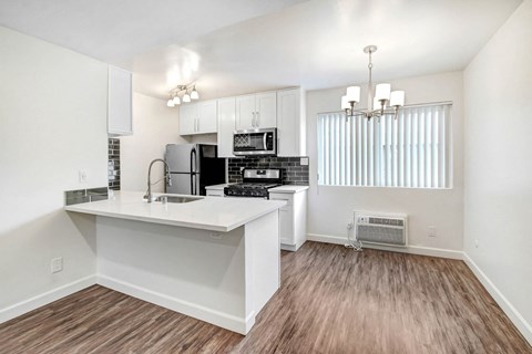 A kitchen with white cabinets and a wooden floor.