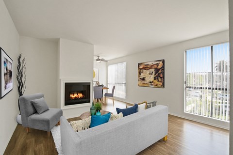 A living room with a grey couch, a fireplace, and a painting on the wall.
