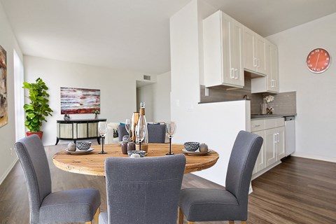 A dining room with a table set for two and a potted plant on the side.