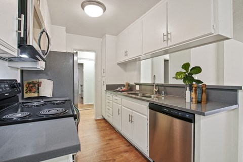 A kitchen with white cabinets and a black stove top.