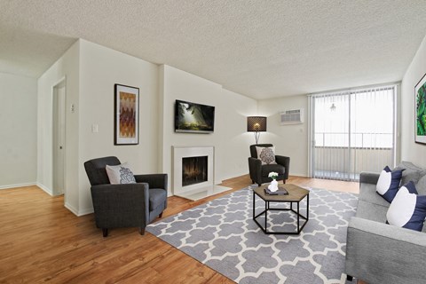 A living room with a fireplace and a grey couch.