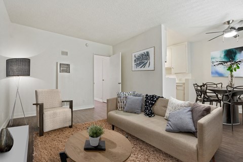 A living room with a beige couch, a coffee table, and a dining table with chairs.