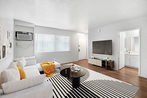 A living room with a white couch and a black and white striped rug.