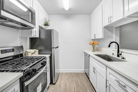 A modern kitchen with white cabinets and stainless steel appliances.