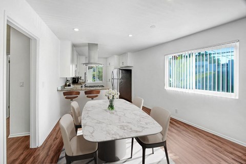 a dining area with a table and chairs and a kitchen in the background