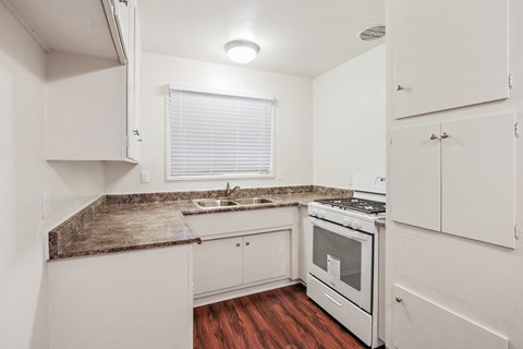 A kitchen with white cabinets and a granite countertop.