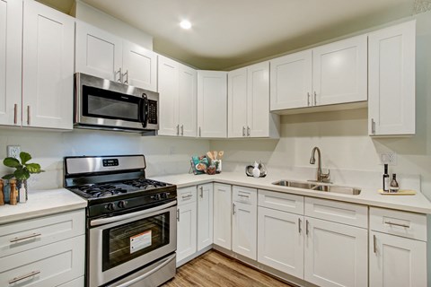 A kitchen with white cabinets and a stainless steel stove.
