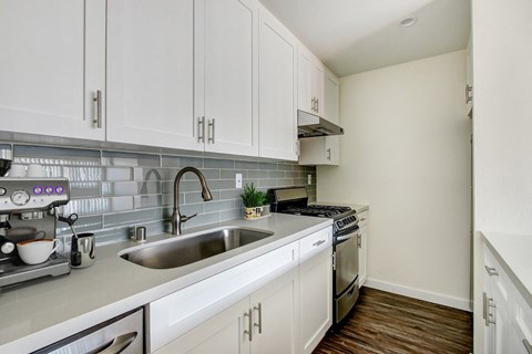 A kitchen with white cabinets and a grey backsplash.