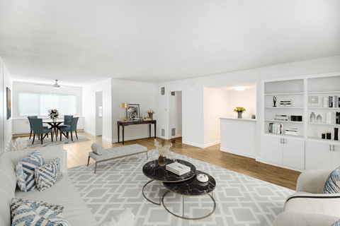 A living room with a white couch, a coffee table, and a dining table with chairs.