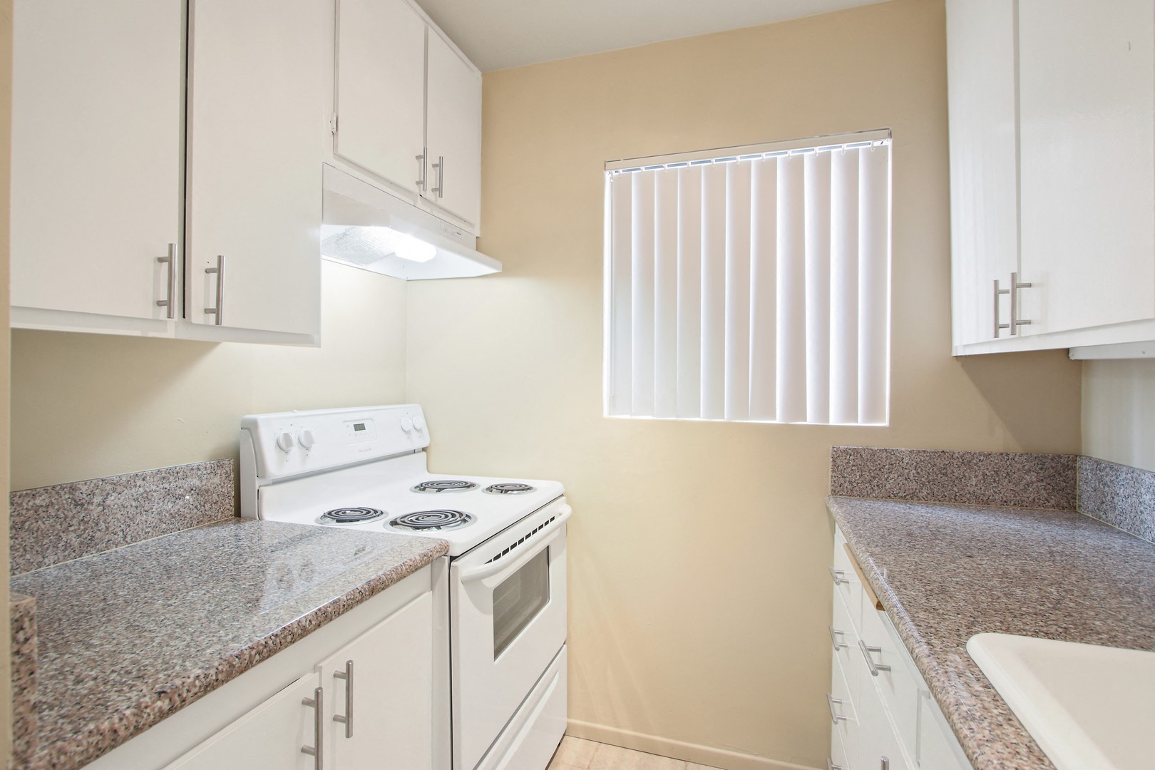 A kitchen with a white stove and cabinets.