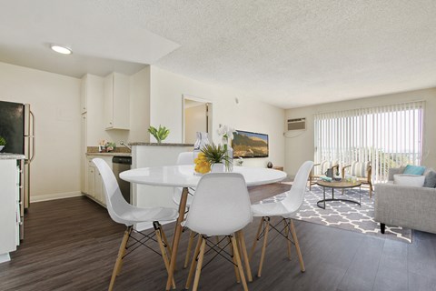 A white dining table with four chairs in a modern kitchen.