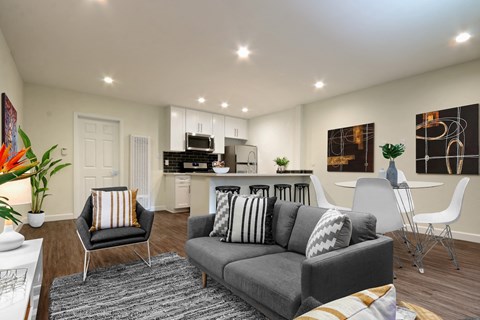 A modern living room with a grey sofa and a kitchen in the background.